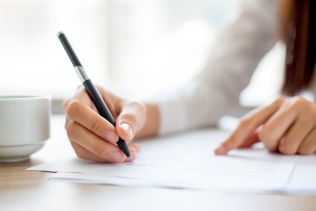 hand-of-businesswoman-writing-on-paper-in-office_1262-2119